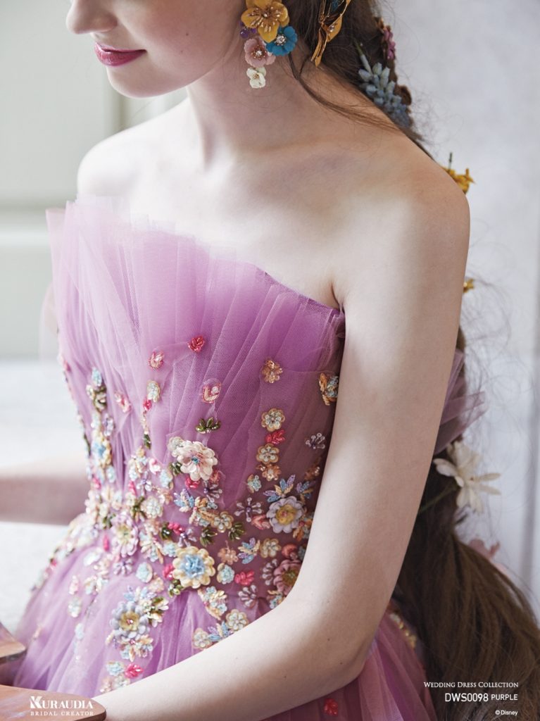 DWS0098（パープル）「ラプンツェル」の長い編み込みヘアーに飾られたカラフルな小花を、繊細でクチュール感あふれるフラワーモチーフで表現しています。「ラプンツェル」カラーのパープルやピンクを重ね合わせた美しい色合いも、大人の女性の心をくすぐるロマンティックなドレスです。