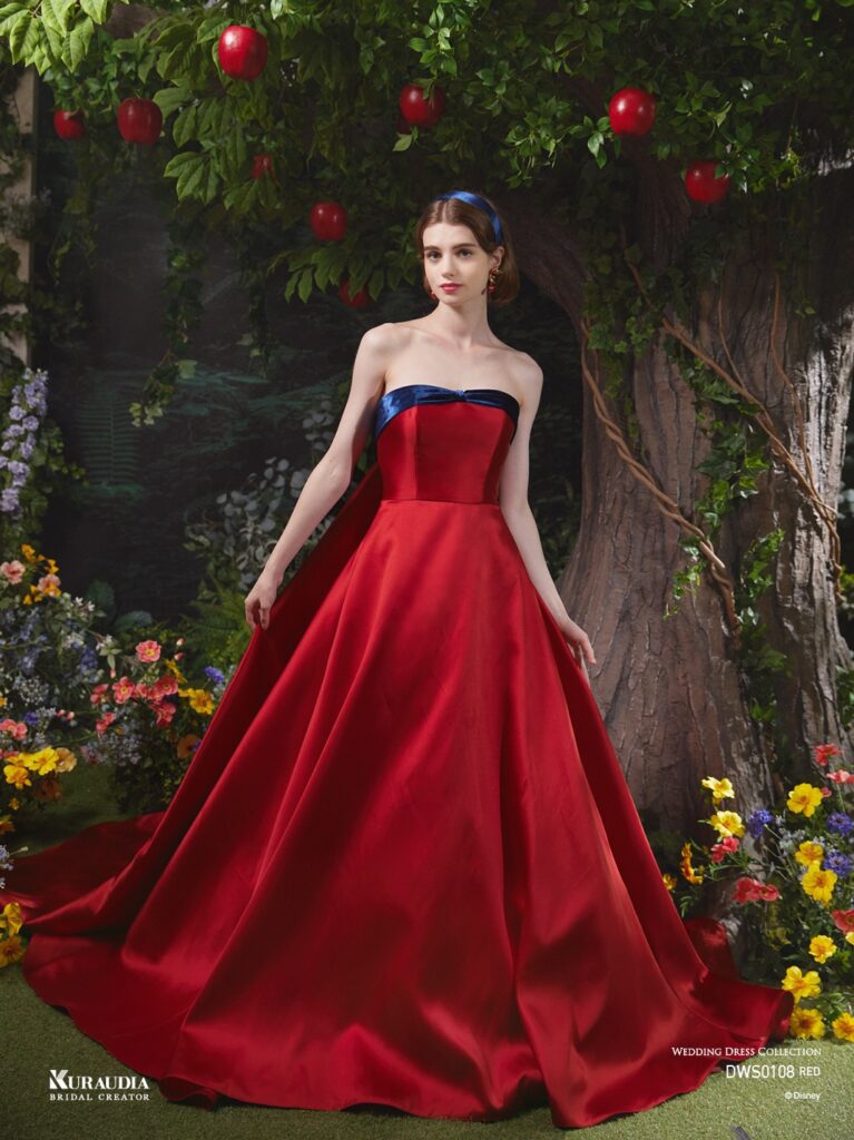 DWS0108 （RED ）| 上質な赤の色合いの美しいシルクミカドを使用し、大きなパフスリーブデザインで「白雪姫」の象徴的なリンゴを表現。 胸元のネイビーのベルベットリボンや、バックスタイルのロングマントで「白雪姫」らしさを感じさせるエレガントな1着です。