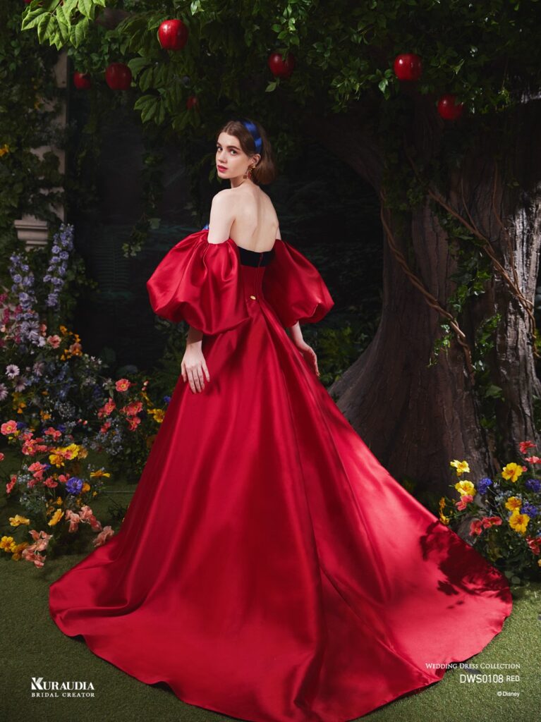 DWS0108 （RED ）| 上質な赤の色合いの美しいシルクミカドを使用し、大きなパフスリーブデザインで「白雪姫」の象徴的なリンゴを表現。 胸元のネイビーのベルベットリボンや、バックスタイルのロングマントで「白雪姫」らしさを感じさせるエレガントな1着です。