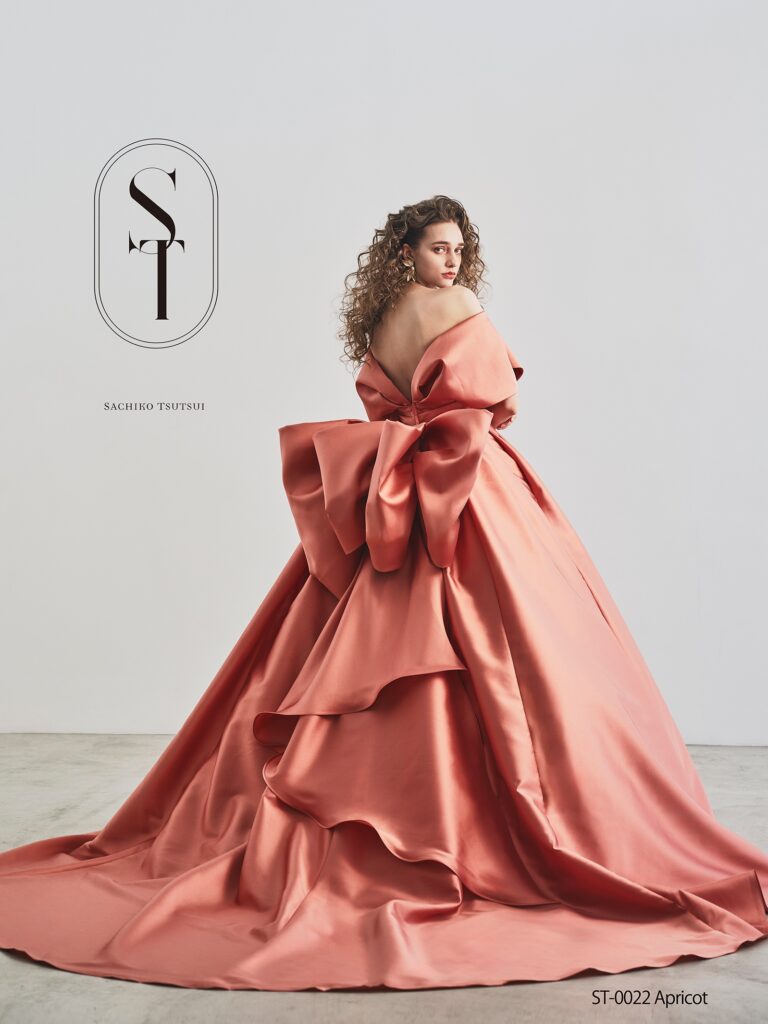 ST-0022（アプリコット） | シルクタッチの上質な光沢感が美しいインポートミカドを使用し、身頃やバックスタイルの立体的なリボンが印象的。平面では表現が難しく、高いパターン技術力でデコルテを美しく、ウエストを細く見せる調整を何度も操り返し重ね、素材の美しさを最大限活かした上品で華やかな一着です。