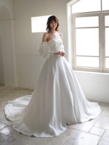 MK-012（オフホワイト）| 独特のとろみがあるトリアセテートミカドをふんだんに使ったAラインのシンプルドレス。スカートの接ぎ線を少なくし、生地の落ち感がスカートのシルエットに表現されるようなカッティングにしました。前中心から後ろにかけて切り替え位置を低くした変形ドロップウエストで、前中心は下にすっきり落ちるデザインでお腹のふくらみをカバーし、脇からボリュームを出すことで華奢なウエストを強調するパターンにこだわった１着です