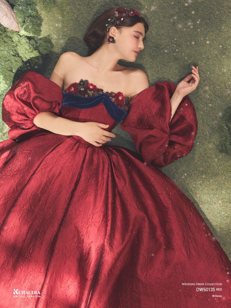 DWS0135 Red 「Snow White」| 「白雪姫」の赤いリップを思わせるジャガード素材を贅沢に使用した、気品あふれる1着です。胸元にはアンティークさを感じる フラワーモチーフと、ネイビーのベルベットリボンをあしらい、「白雪姫」を上品に演出します。りんごのようにふっくらシルエットの パフスリーブも魅力の一つです。※袖は取り外し可能です。