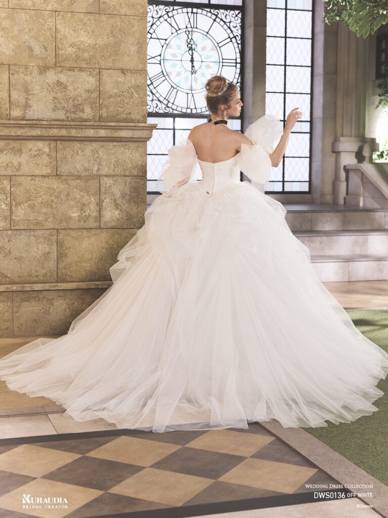 DWS0136 Blue / Off White 「Cinderella」| 「シンデレラ」の魔法にかけられる煌めきを、2種類のグリッターチュールを贅沢に重ね合わせて表現した、ロマンティックな一着 です。「シンデレラ」の衣装からインスパイアされたボリュームのあるタッキングスカートでモードな一面もあります。リボン風の ボリュームショルダーが愛らしさもプラスするプリンセスドレスです。※袖は取り外し可能です。