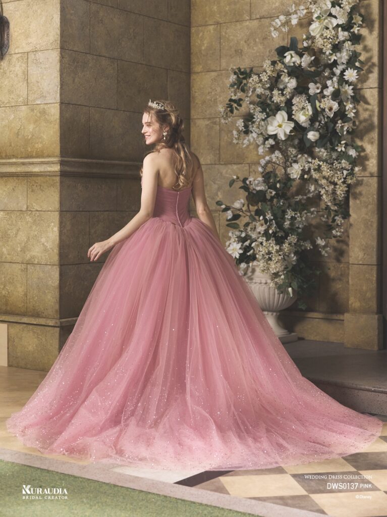 DWS0137 Pink 「Princess Aurora」| 「オーロラ姫」からインスパイアされたエレガントで女性らしいローズピンクのチュールドレスです。肩にのるフリルケープや、 ローズをイメージしたスパンコールのモチーフがポイントです。ローウエストのV字切り替えでシルエットをより美しく演出し、スカートには魔法がかかったようなグリッターが煌めき、上品な印象に。※ケープは取り外し可能です。