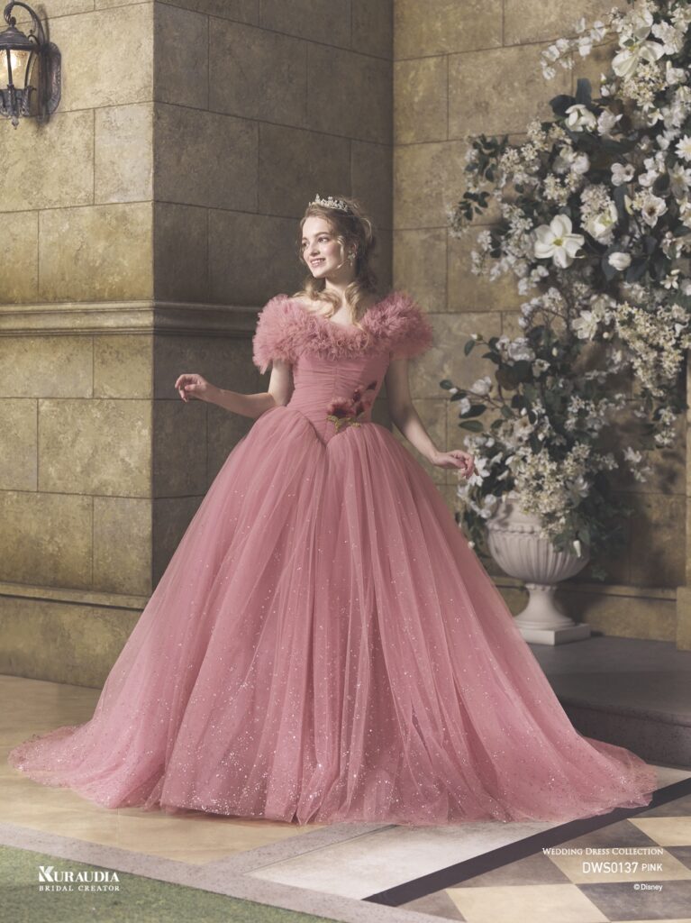 DWS0137 Pink 「Princess Aurora」| 「オーロラ姫」からインスパイアされたエレガントで女性らしいローズピンクのチュールドレスです。肩にのるフリルケープや、 ローズをイメージしたスパンコールのモチーフがポイントです。ローウエストのV字切り替えでシルエットをより美しく演出し、スカートには魔法がかかったようなグリッターが煌めき、上品な印象に。※ケープは取り外し可能です。