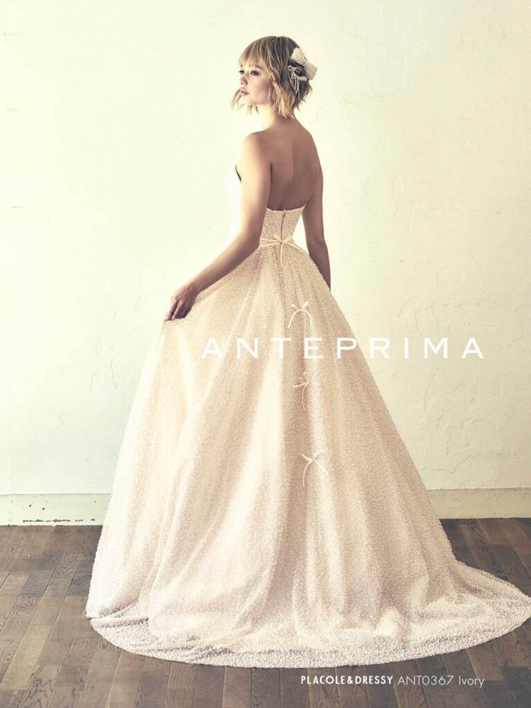 ANT0367（アイボリー/オレンジ） | ジュエルパールグリッターの輝きを全身にまとい、上品さと可憐さをあわせ持つ“現代のプリンセス”を表現。新素材“エアーファブリックオーガン”が、ふんわりと空気を含んだような軽やかなドレープを描きます。ピーチオレンジのやさしい色合いが肌にやわらかく映え、見る人にぬくもりと幸せを届けるような一着です。